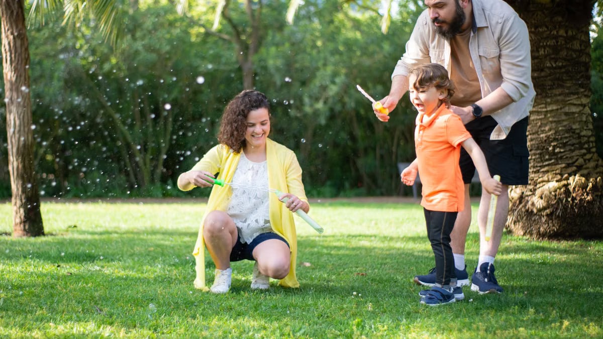 A family enjoys a playful day with bubbles in a sunny park setting.